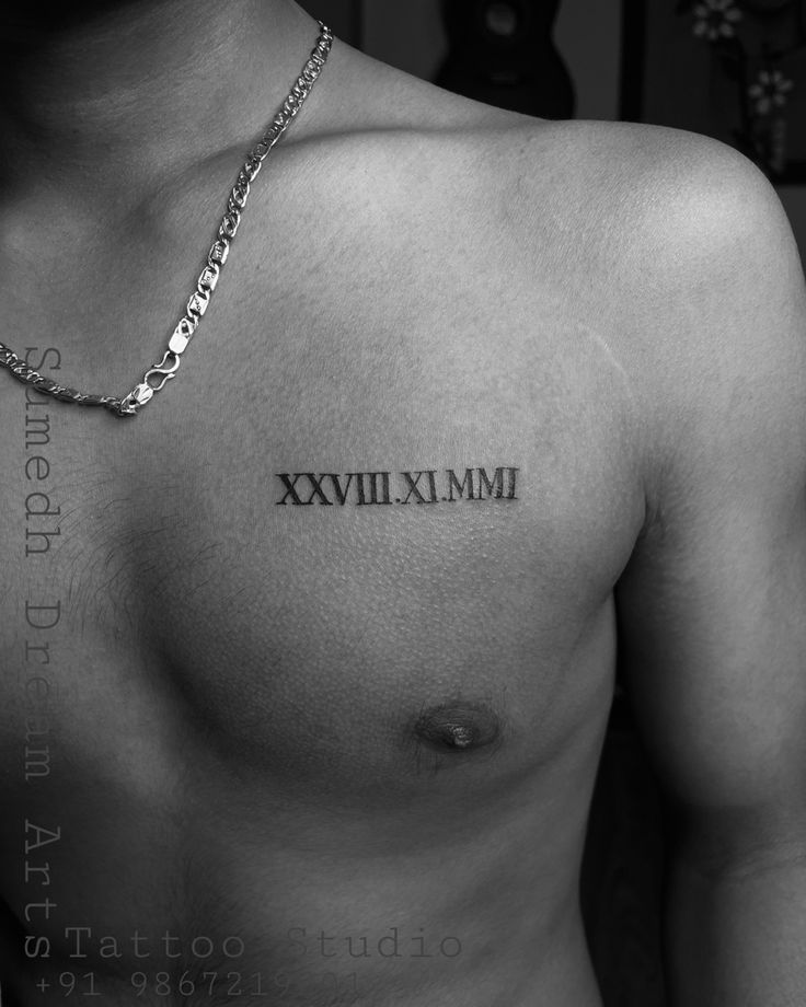 black and white photograph of a man's chest with roman numeral tattoo on it