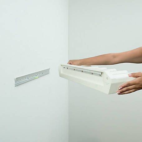 a person holding a white object in front of a wall with a ruler on it