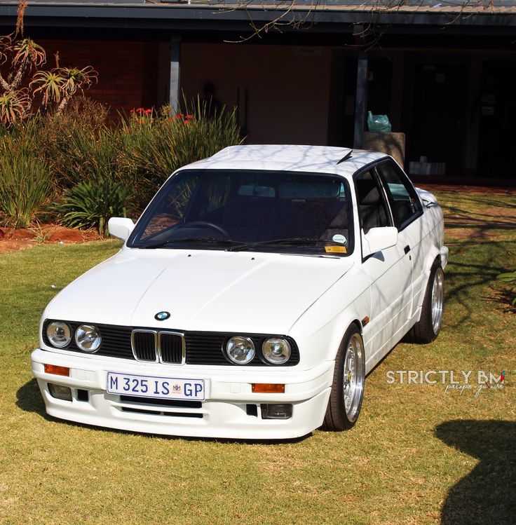 a white car parked in front of a house next to a green lawn and shrubbery