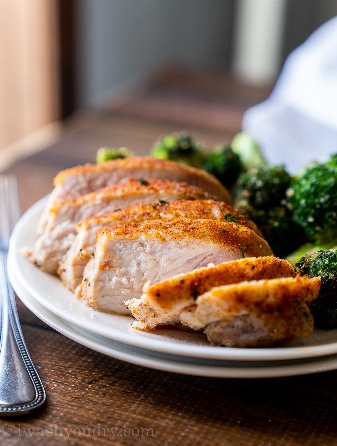 a white plate topped with meat and broccoli on top of a wooden table