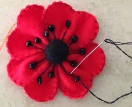 a red flower sitting on top of a white floor next to a black string and thread