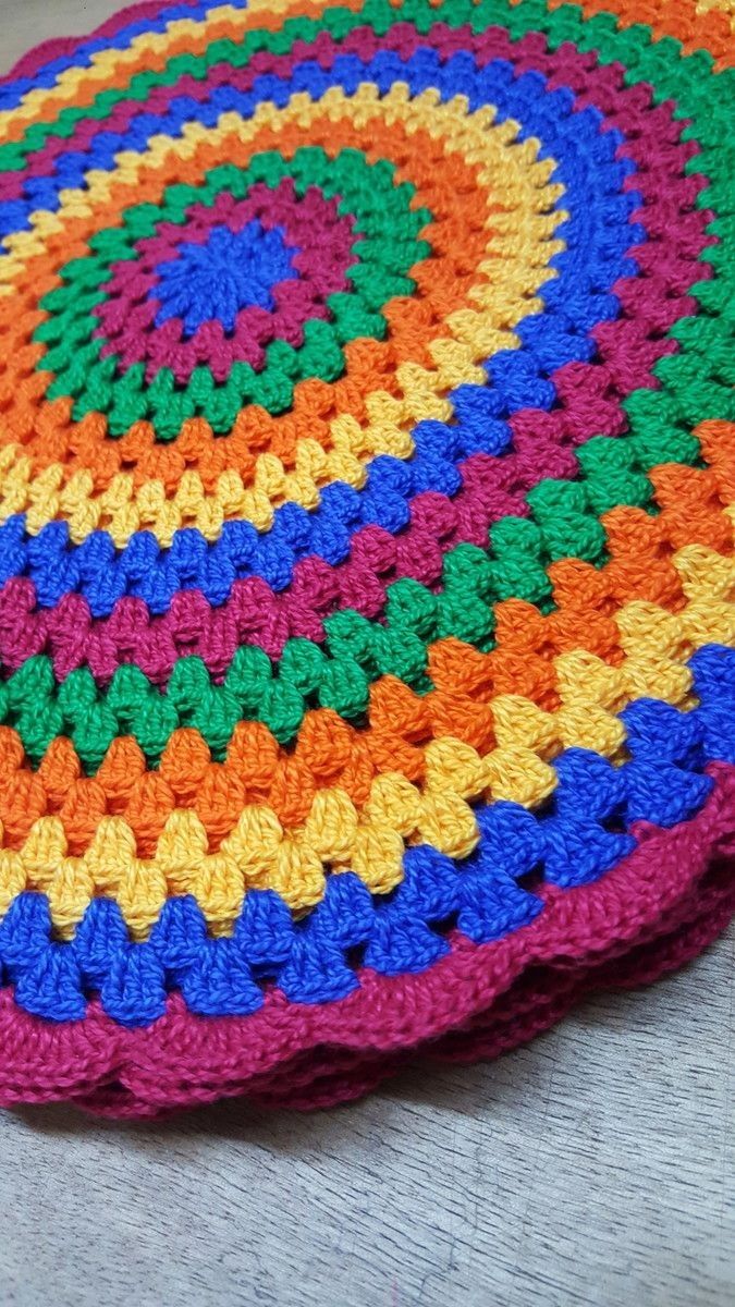 a multicolored crocheted round rug on the floor