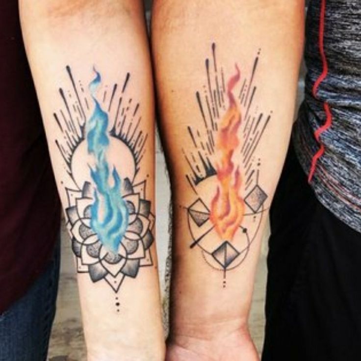 two people with tattoos on their arms holding each other's hands and one has a fire