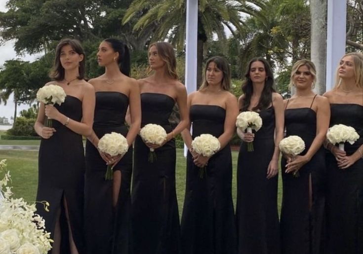 a group of women standing next to each other in front of a white flower arrangement