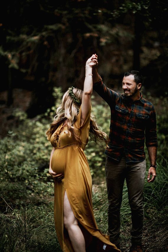 a pregnant woman dancing with her husband in the woods