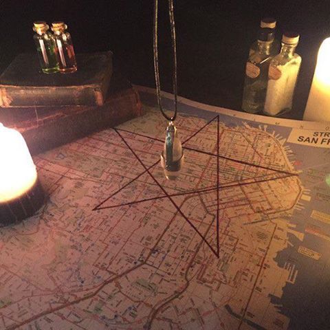 two candles are sitting on top of a map with some bottles in the back ground