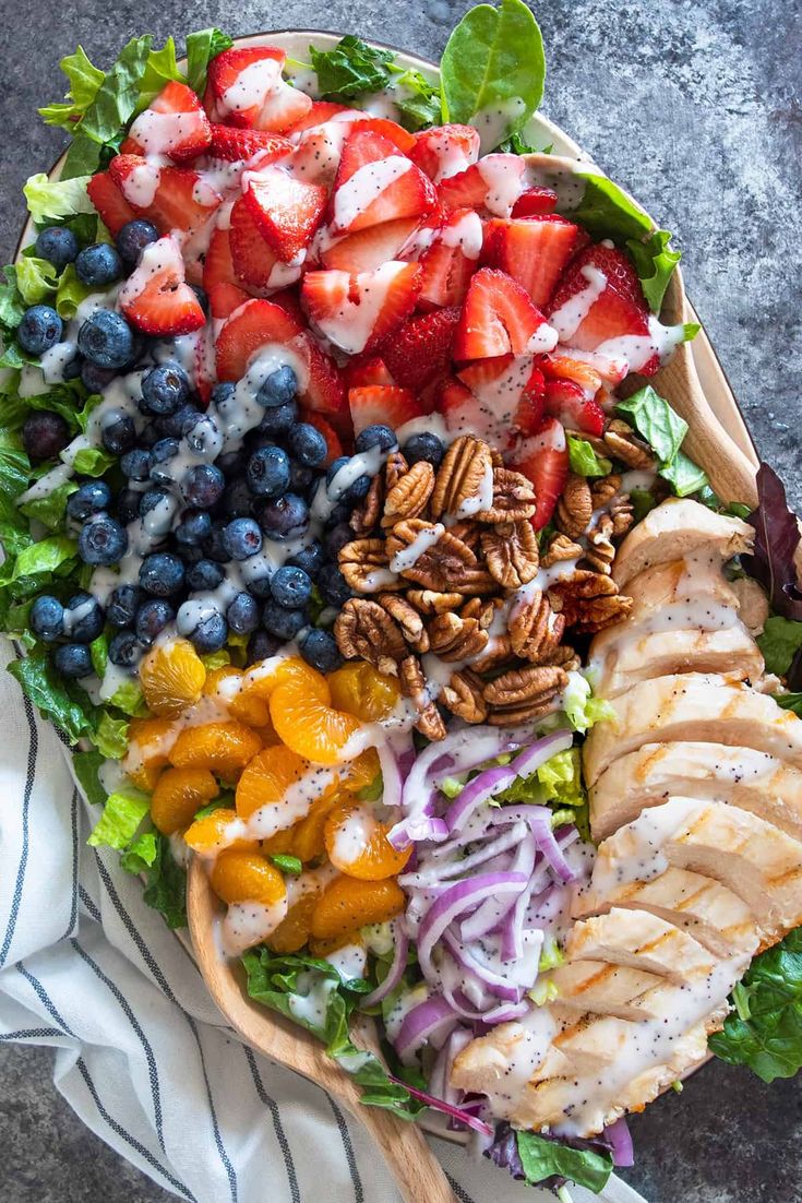 a salad with chicken, strawberries, blueberries, oranges and pecans