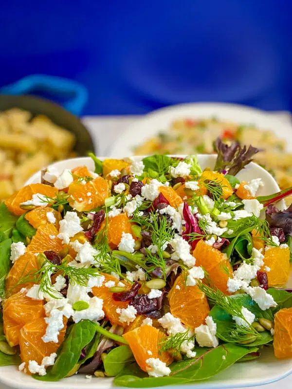 a salad with oranges, feta cheese and spinach is on a white plate