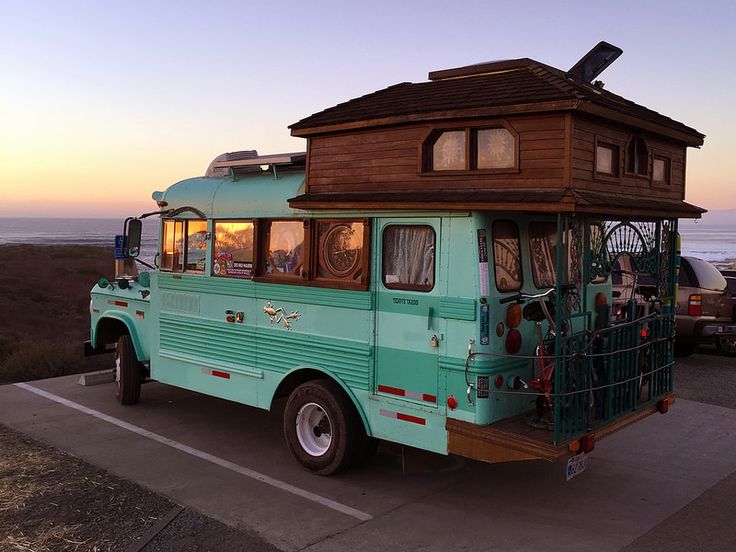 a blue bus with a wooden cabin on the roof