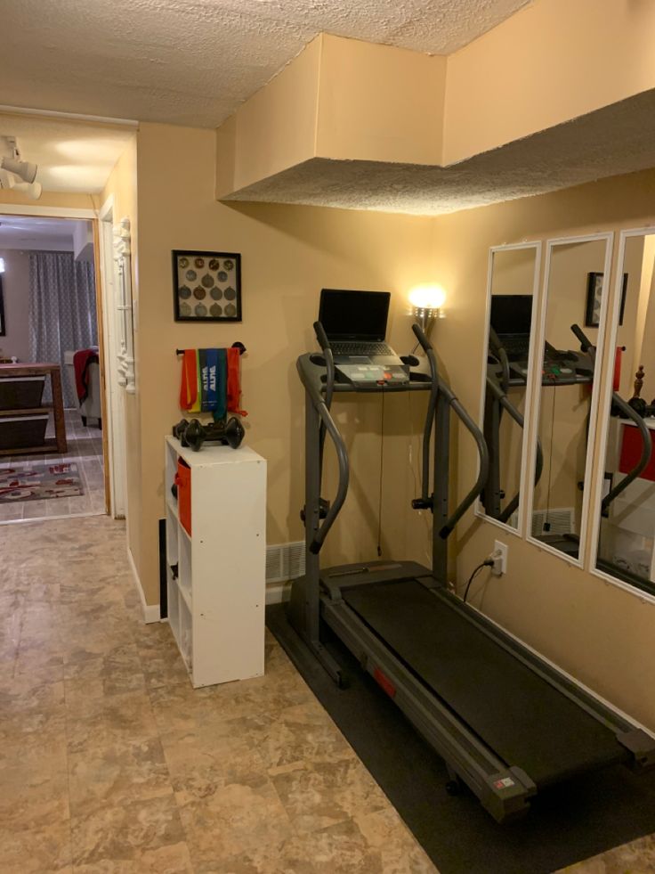 there is a treadmill in the middle of this room with mirrors on the wall