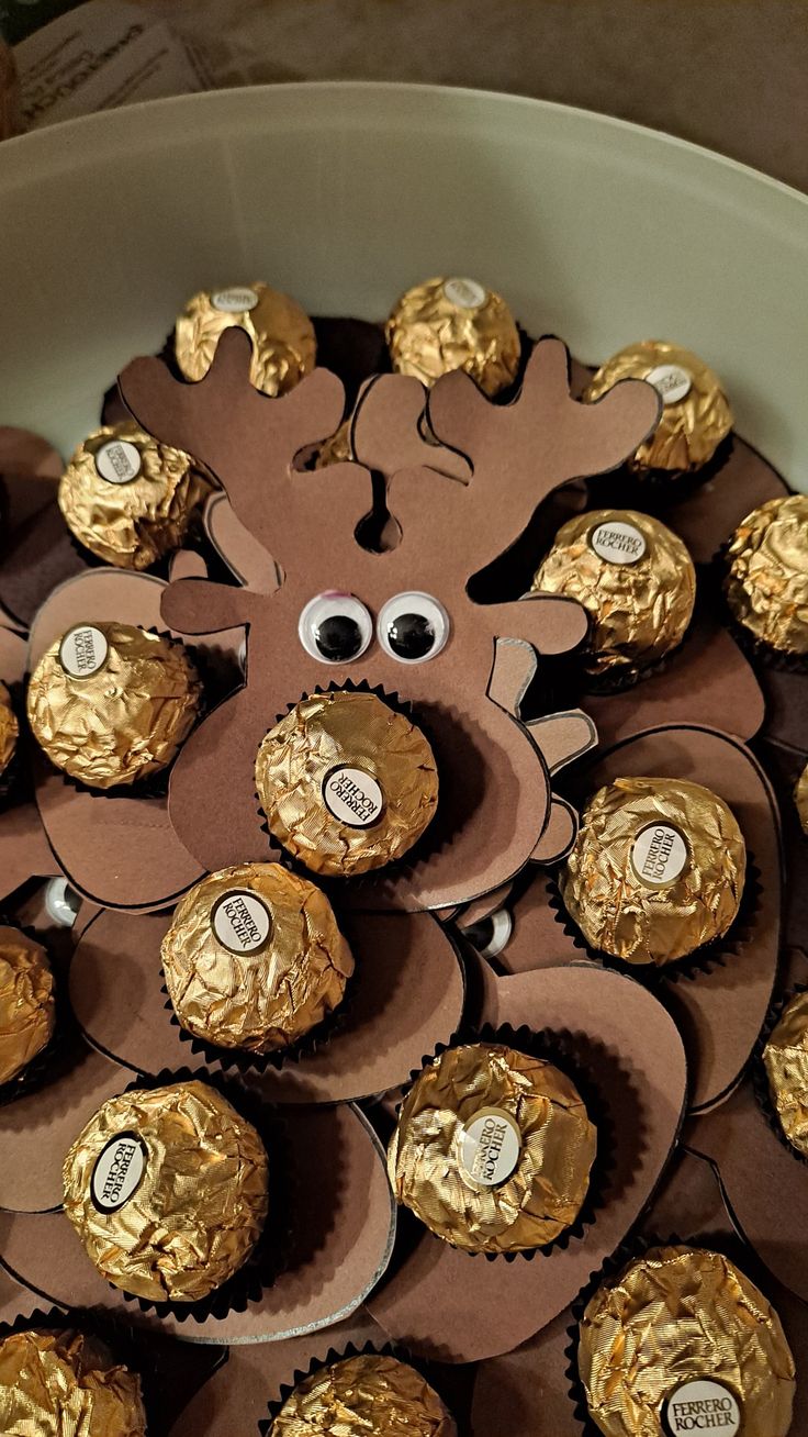 a bowl filled with chocolate covered candies and an animal face made out of gold foil