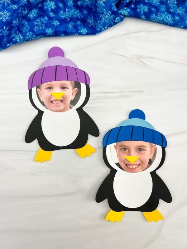 two children's paper cutouts of penguins wearing hats and scarfs, with snowflakes in the background