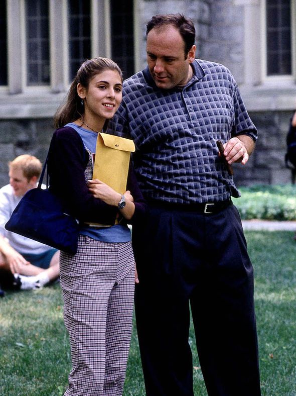 a man standing next to a woman on top of a lush green field in front of a building