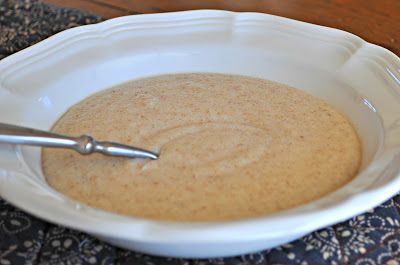 a white bowl filled with brown liquid on top of a table