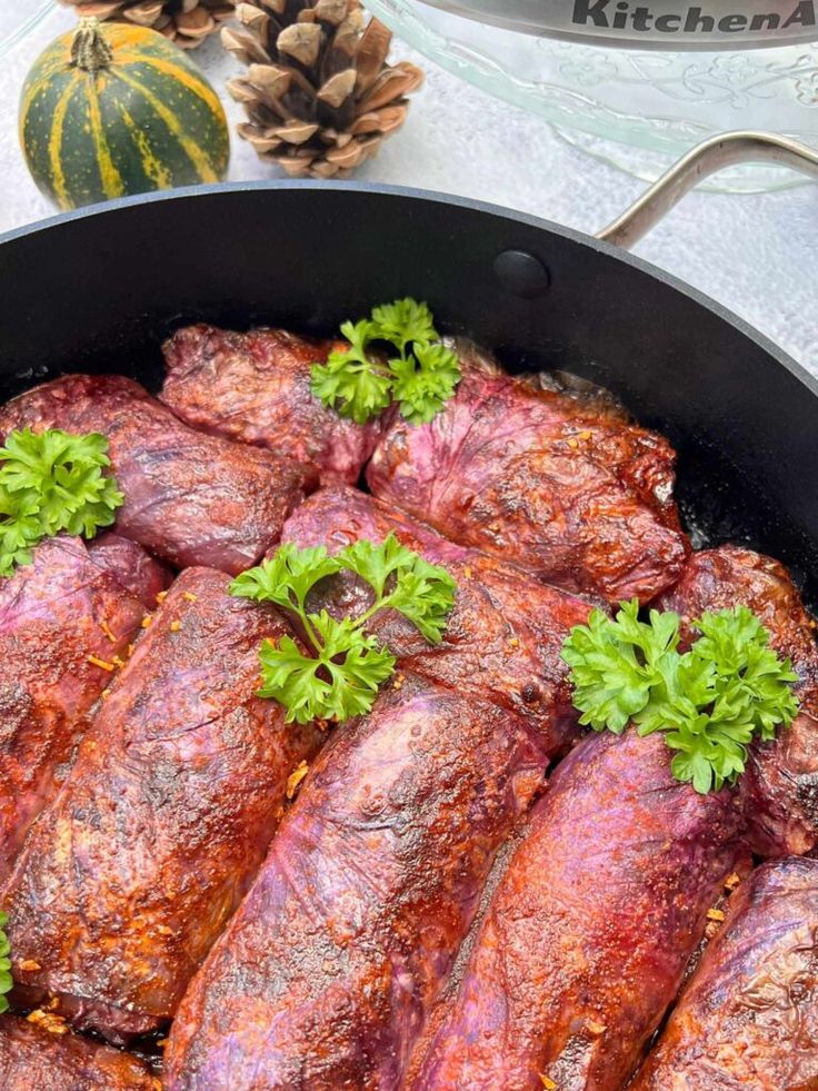 some meat is cooking in a pan with parsley sprigs on the side