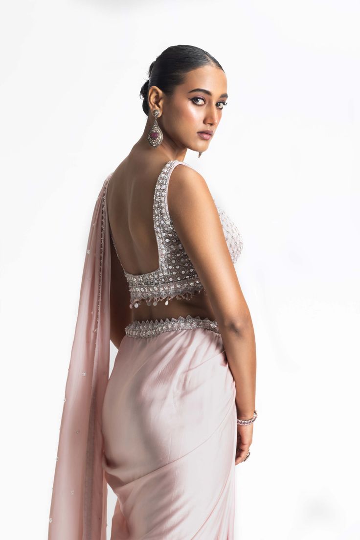 Elevate your style with our rose to blush ombre dyed satin draped sari. The net blouse and satin palla are adorned with tonal sequins, beadwork, and crystals, making it a dazzling choice for any special occasion. Make a graceful entrance and leave a lasting impression in this exquisite ensemble. Sleeveless Silk Saree For Wedding, Sleeveless Cutdana Pre-draped Saree For Wedding, Glamorous Sleeveless Pre-draped Saree For Evening, Glamorous Sleeveless Evening Pre-draped Saree, Elegant Sleeveless Pre-draped Saree With Resham Embroidery, Sleeveless Silk Lehenga For Reception, Sleeveless Silk Blouse Piece With Mirror Work, Silk Sleeveless Blouse For Reception, Sleeveless Silk Blouse For Reception