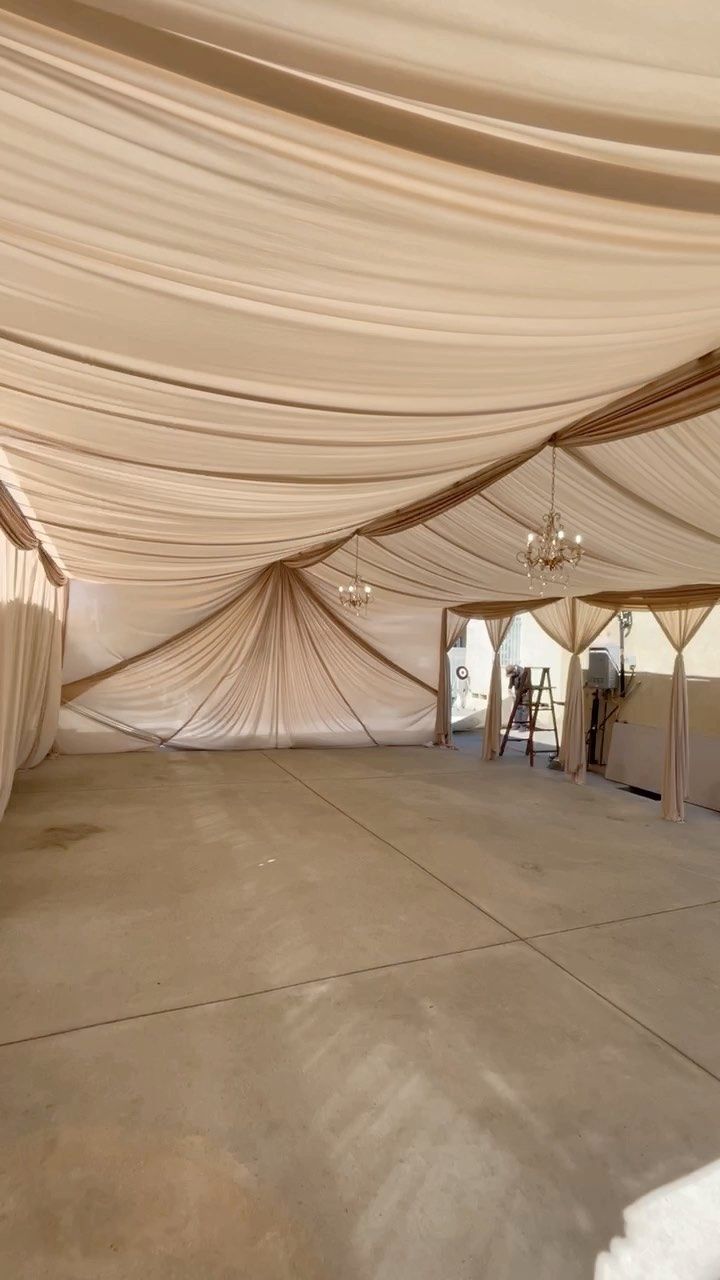 the inside of a large tent with white walls and drapes on it's sides