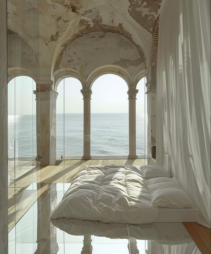 a bed sitting in the middle of a room next to an ocean