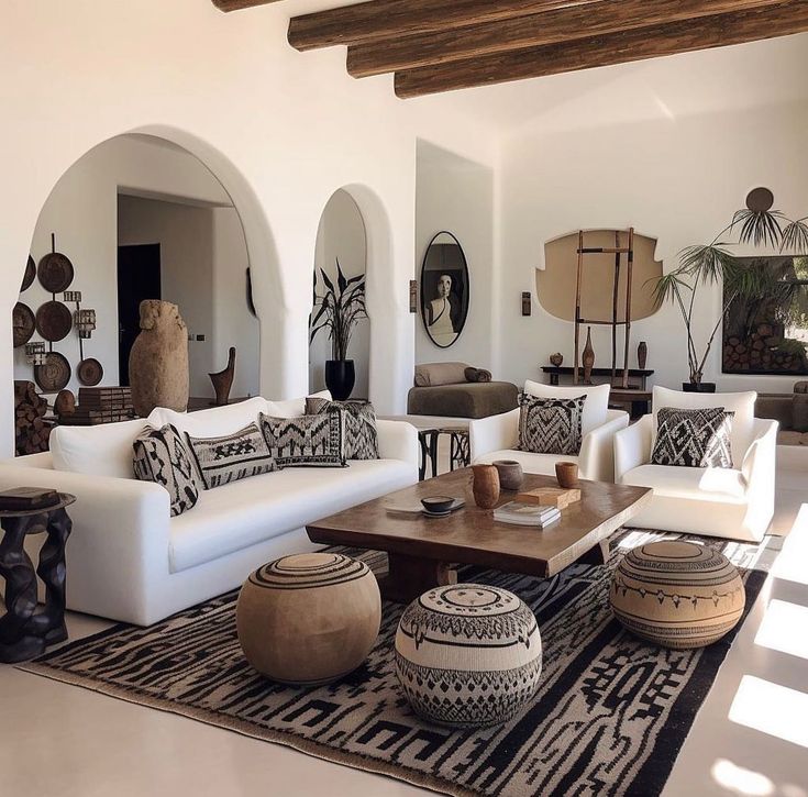 a living room filled with white furniture and lots of pillows on top of a rug