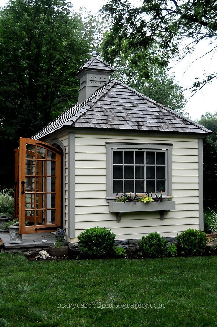 a small white shed sitting in the middle of a yard