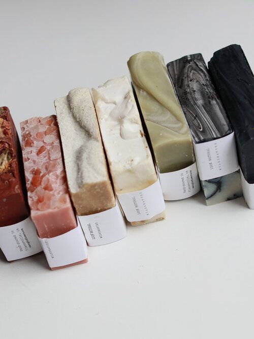 five different types of soaps are lined up in a row on a white surface