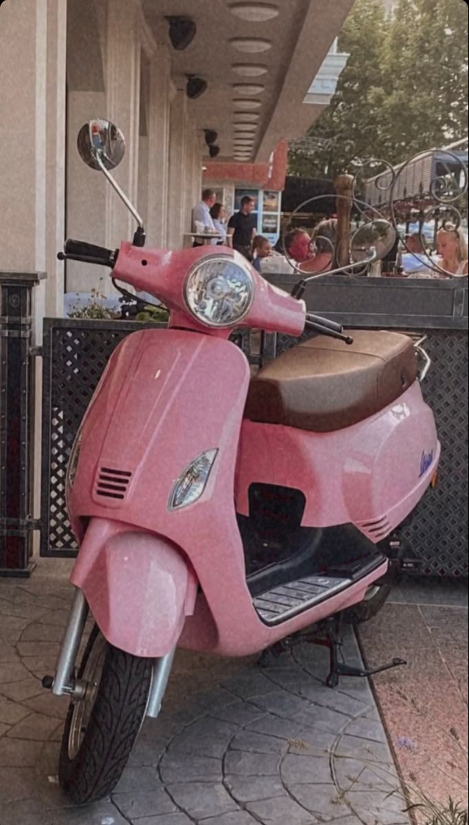 a pink scooter is parked on the sidewalk