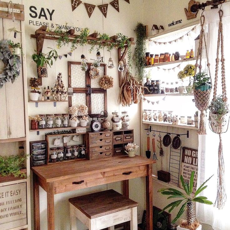 a room filled with lots of potted plants and hanging decorations on the wall above a wooden table