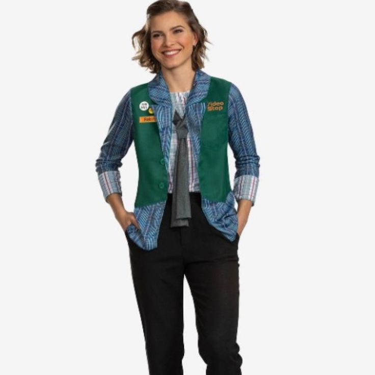 a woman standing with her hands on her hips wearing a green vest and plaid shirt