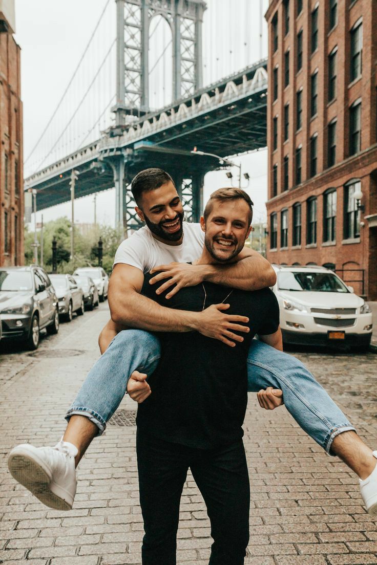 two men are holding each other in the middle of an alleyway with a bridge in the background