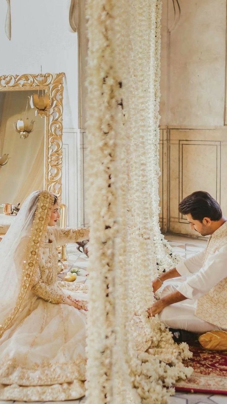 a bride and groom sitting on the floor in front of a mirror