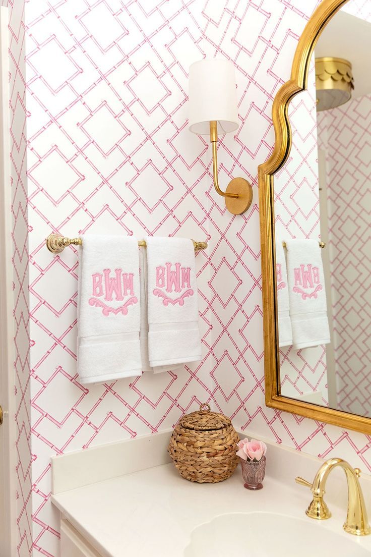 a bathroom with pink and white wallpaper, gold fixtures and towels on the rack