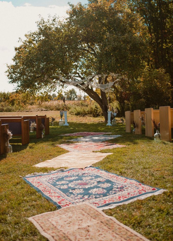 an outdoor area with rugs and trees in the background