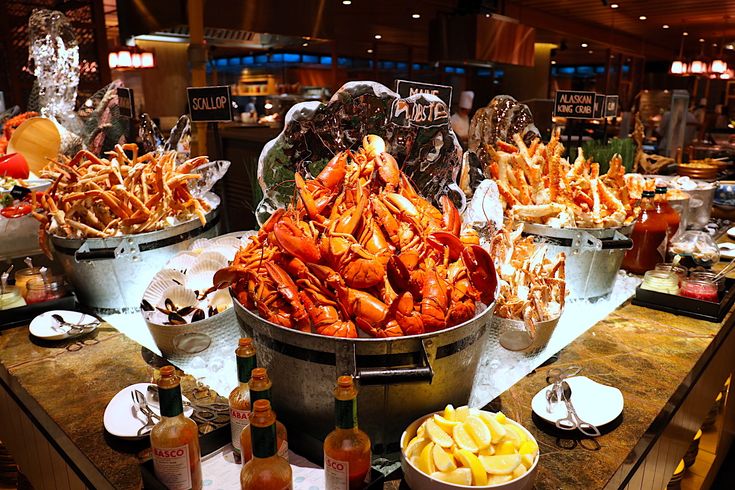 there are many different types of food on the buffet table at this restaurant, including lobsters and chips