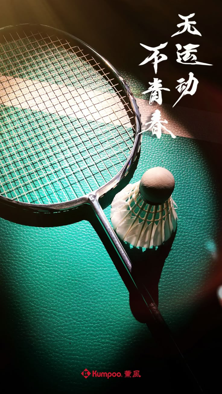 a close up of a tennis racket on a green surface with chinese characters in the background