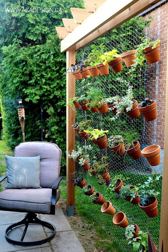 an outdoor garden with potted plants and a chair in front of the trellis