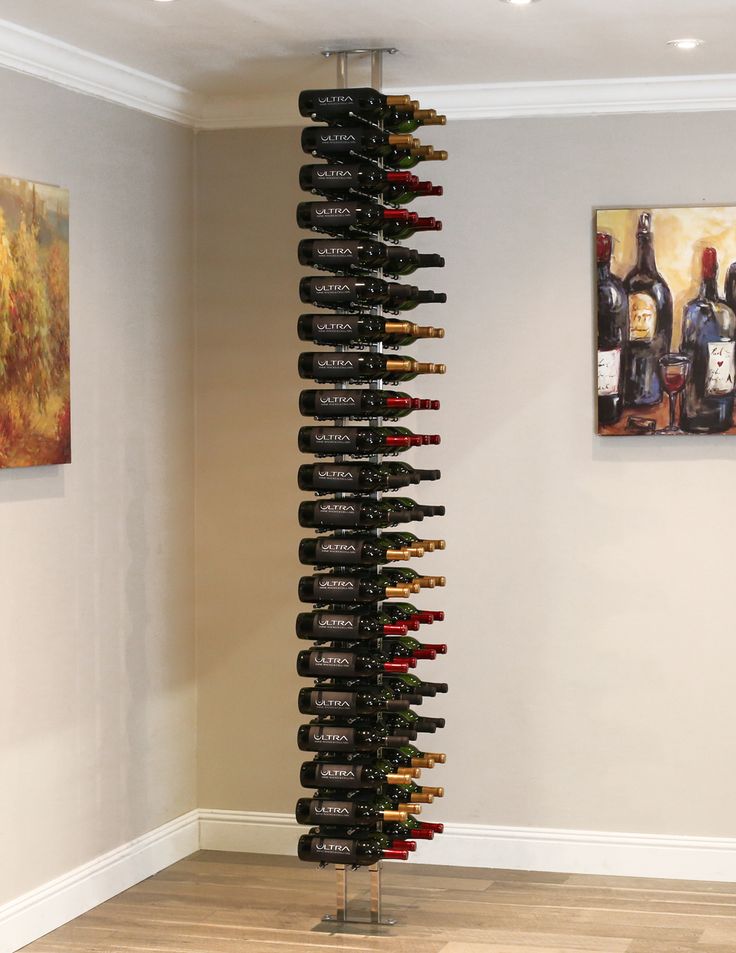 a tall wine rack in the corner of a room with paintings on the wall behind it