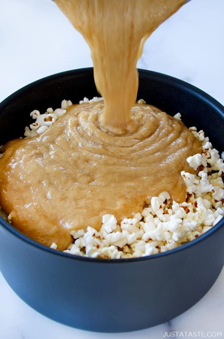 a person pouring peanut butter on top of popcorn