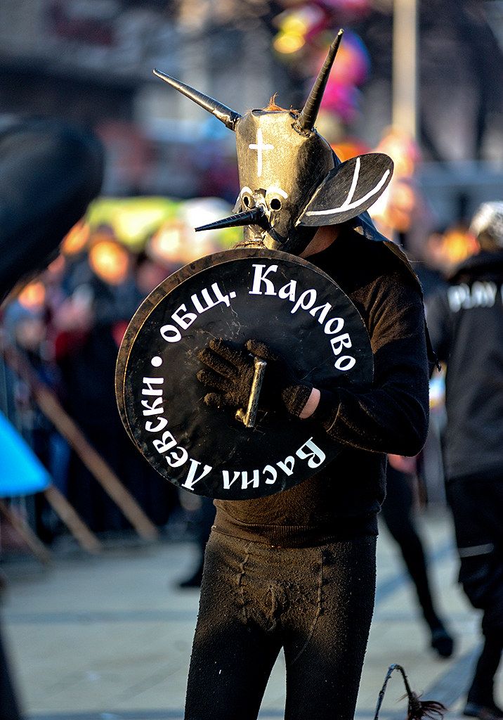 a man wearing a mask and holding a shield with writing on it while standing in the street