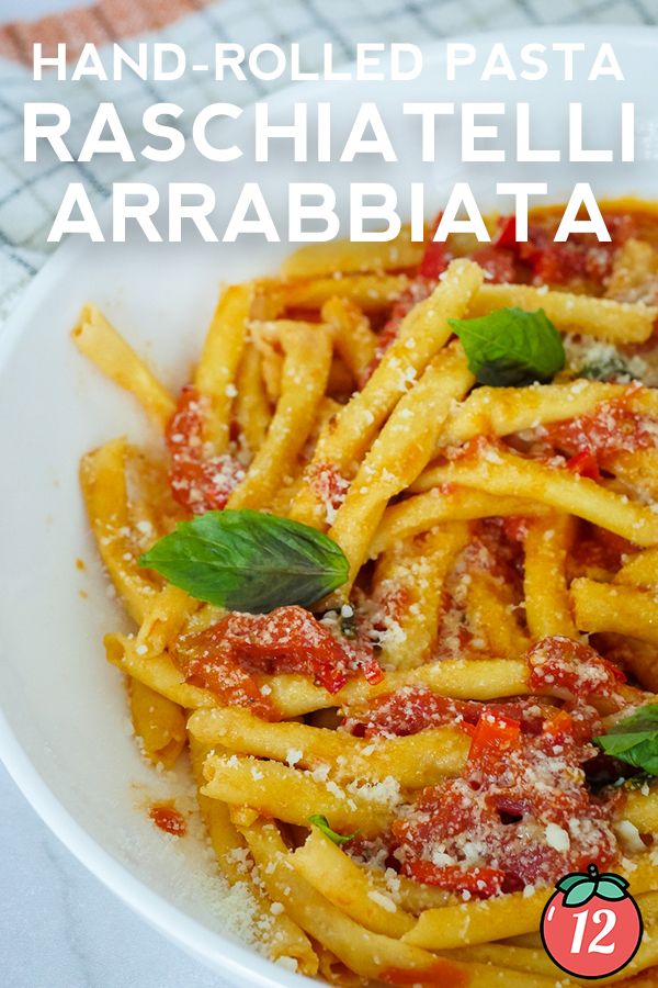 pasta with tomato sauce and basil leaves in a white bowl on top of a table