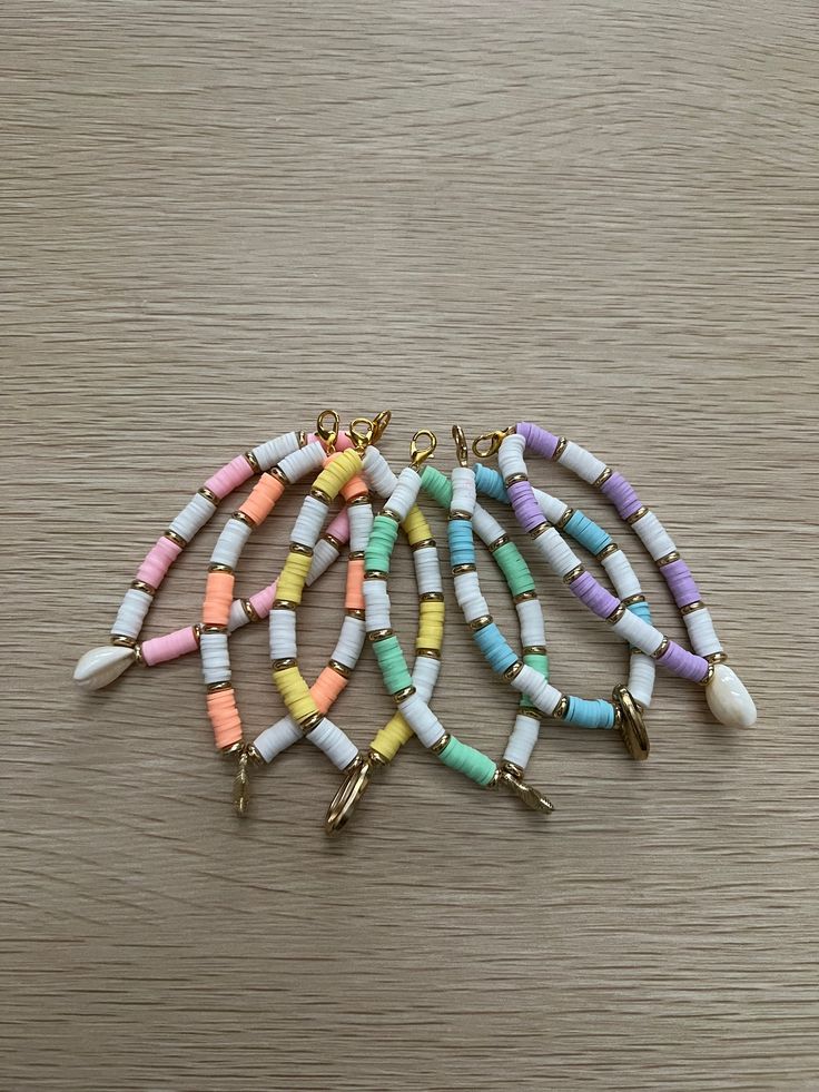 multicolored beaded bracelets on wooden table with gold earring hooks and chain