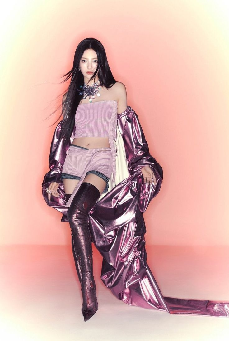 a woman with long black hair wearing purple clothes and thigh high boots, posing in front of a pink background