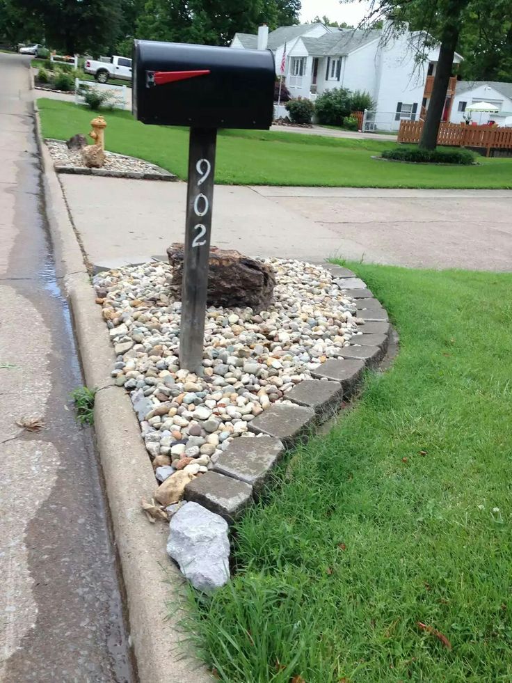 a mailbox sitting on the side of a road next to some grass and rocks