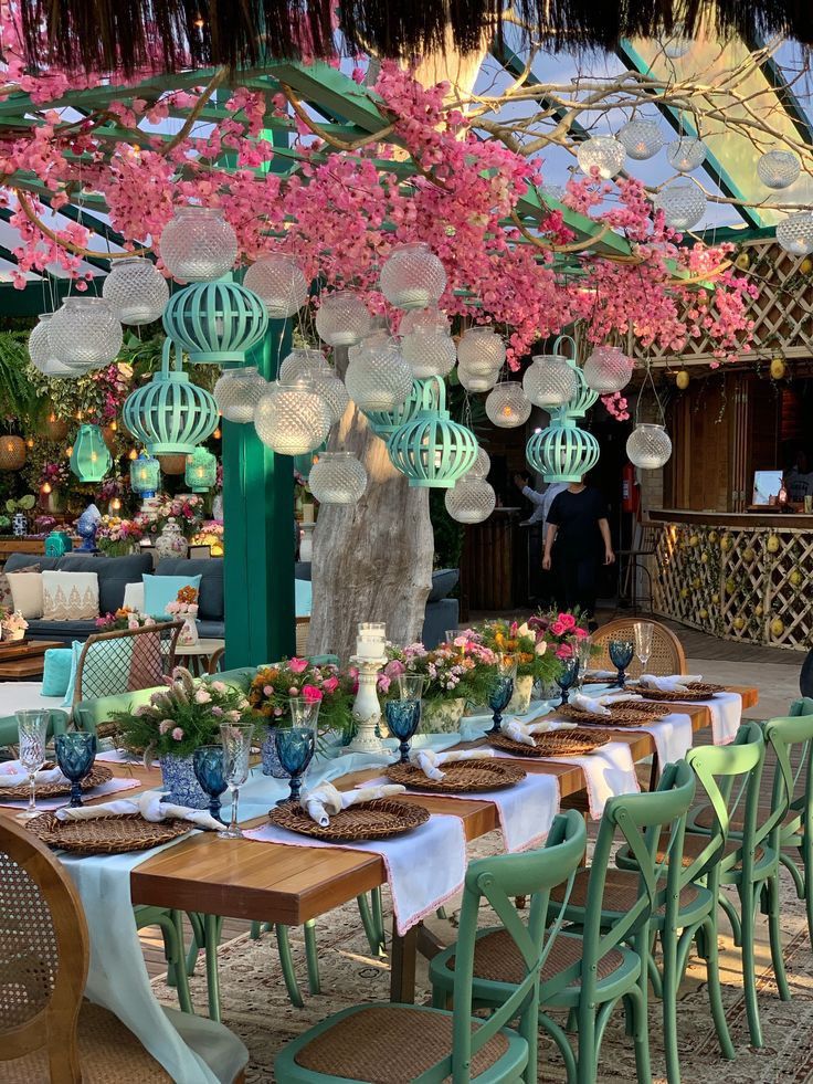 an outdoor dining area with tables, chairs and lanterns hanging from the ceiling above them