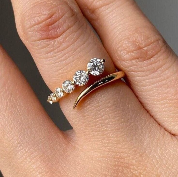 a woman's hand with a gold ring and three diamond rings on top of it