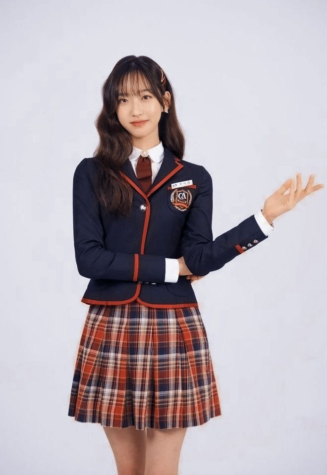 a girl in a school uniform is holding her hands out and posing for the camera