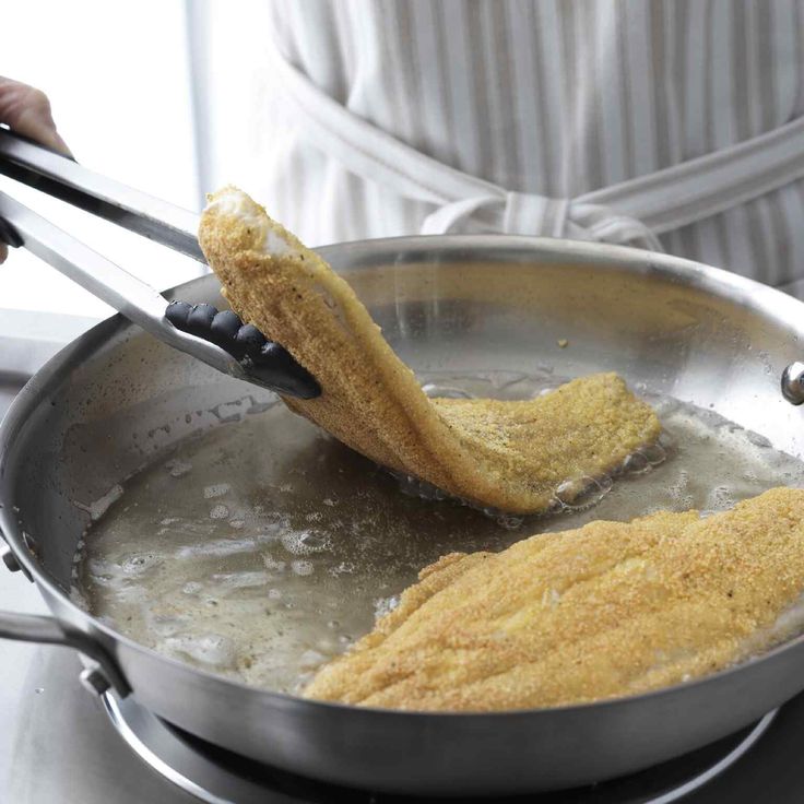 a frying pan with some food cooking in it and someone holding a spatula