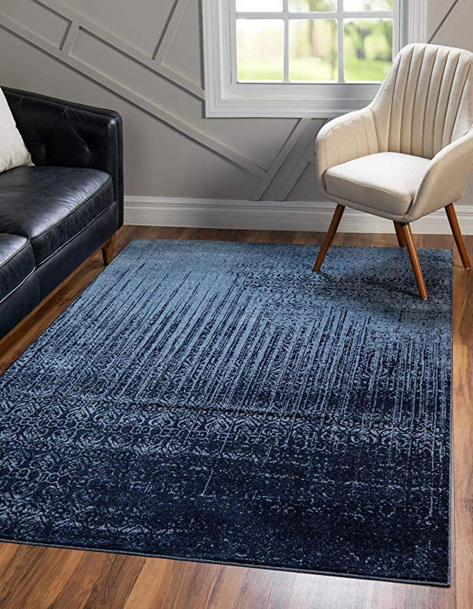 a living room with two black leather chairs and a blue rug in front of a window