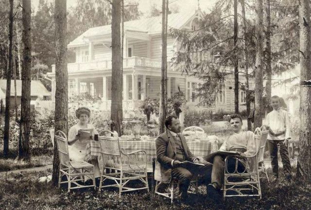 an old black and white photo of people sitting at a table in the woods