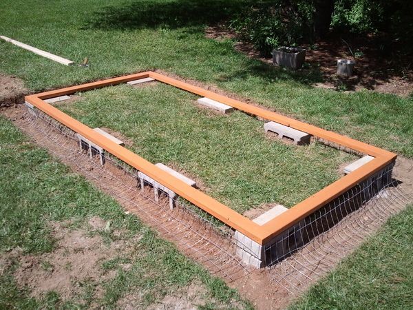 an outdoor area with grass and benches in the middle, surrounded by dirt and wood