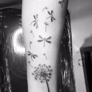 a black and white photo of a woman's arm with dragonflies on it